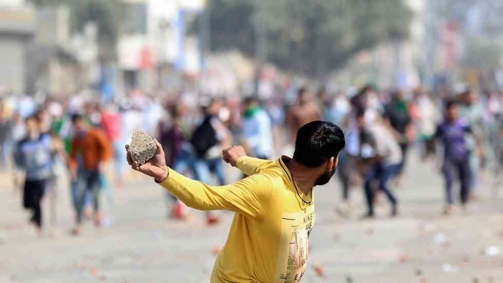 A man throws a stone at rival demonstrators during a clash over a new citizenship law in New Delhi, India, February 24, 2020