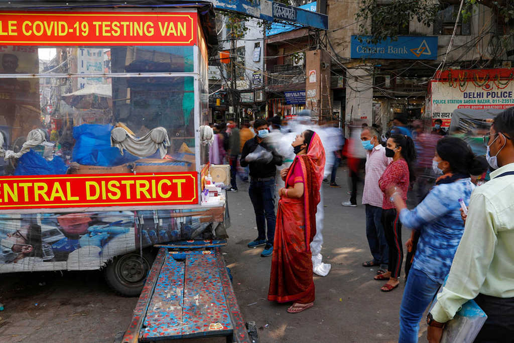 A healthcare worker wearing personal protective equipment (PPE) collects a swab sample from a woman amidst the spread of the coronavirus disease (COVID-19), at a wholesale market, in the old quarters of Delhi, India, November 17, 2020